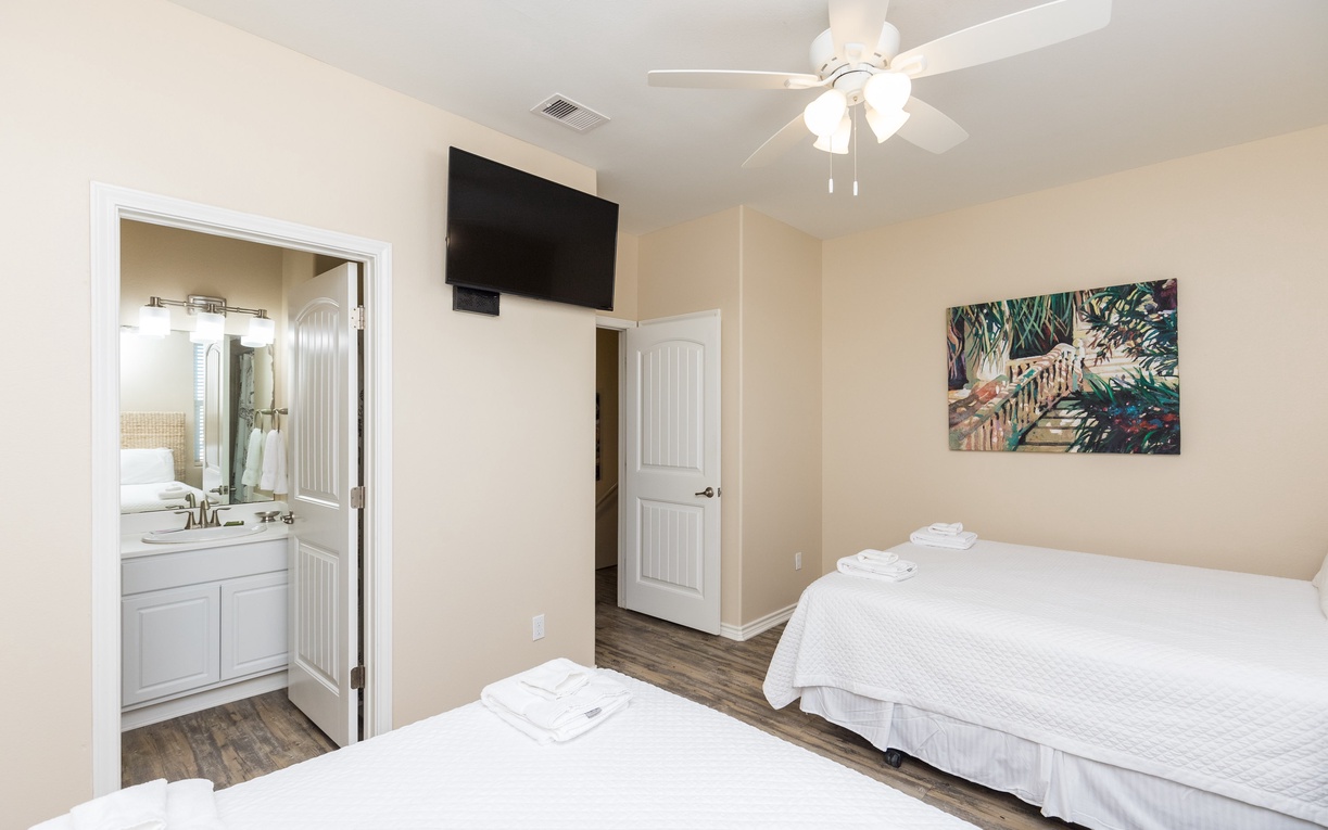 Unwind in your peaceful bedroom with twin beds, ceiling fan, and private bathroom access for ultimate comfort.