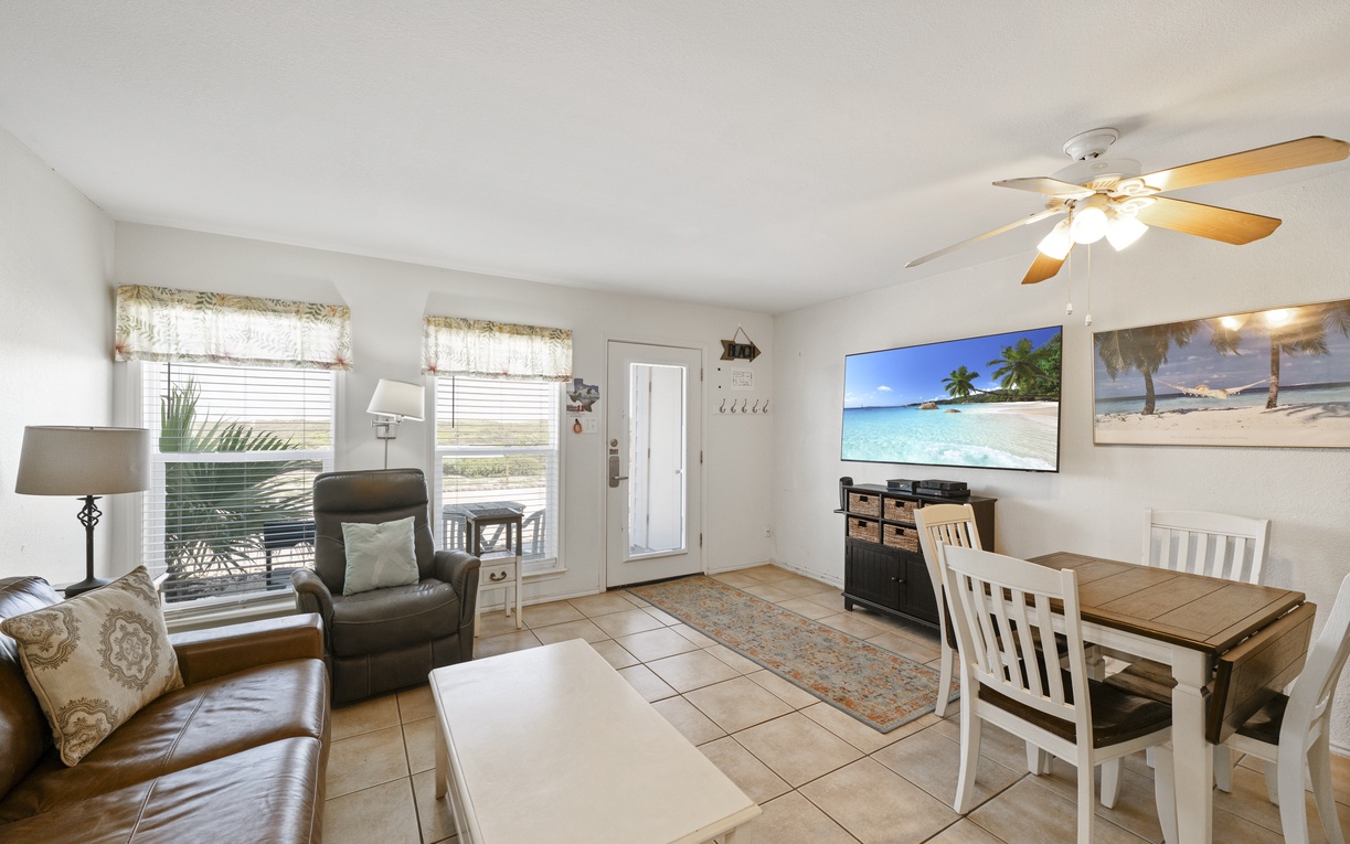Relax in your bright, coastal-themed living space with comfortable seating, dining area, and tropical artwork creating the perfect beach getaway atmosphere.