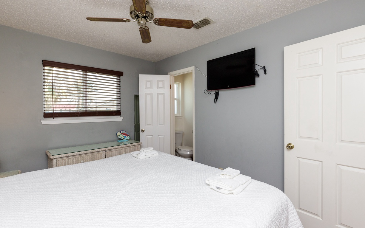 Unwind in your peaceful bedroom with soft linens, ceiling fan, flat-screen TV, and private bathroom access.