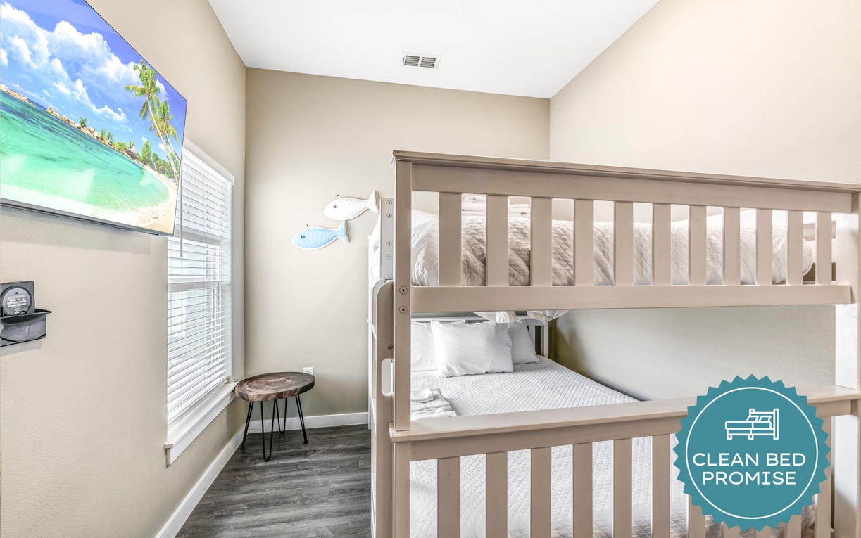 Cozy bunk bed room perfect for kids, featuring tropical wall art and clean linens for restful nights.