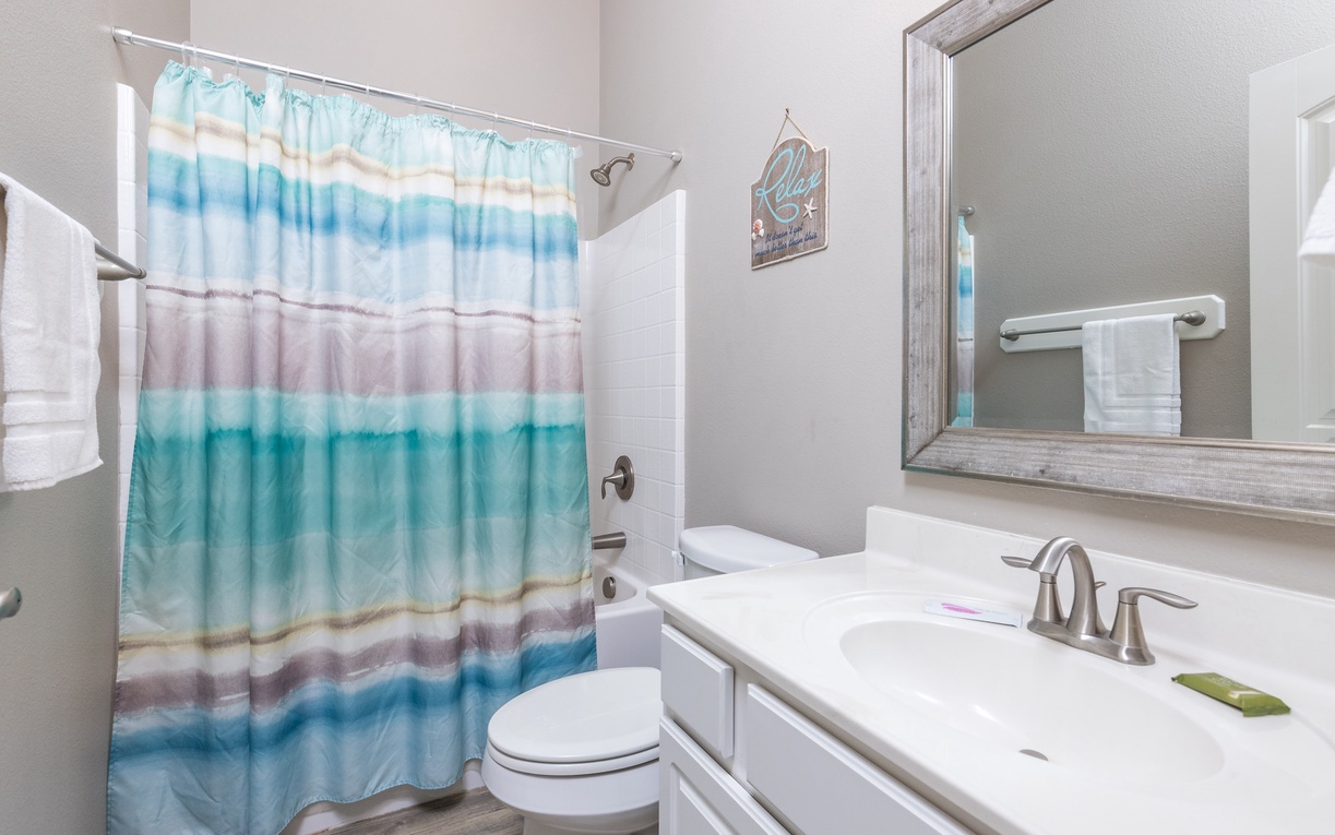 Your private bathroom features ocean-inspired touches with a refreshing shower-tub combo and fresh towels ready for your stay.