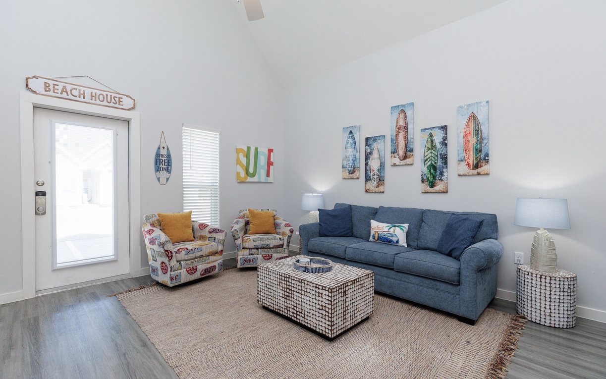 Sink into your cozy beach-themed living room where surfboard art and nautical touches create the perfect coastal retreat atmosphere.