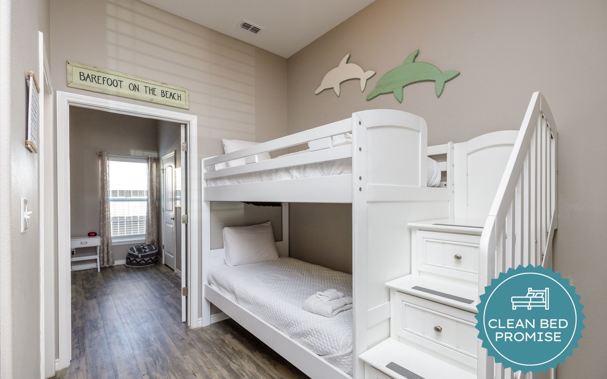 Your kids will love this beach-themed bunk room with playful dolphin decor and cozy beds for sweet dreams after beach adventures.