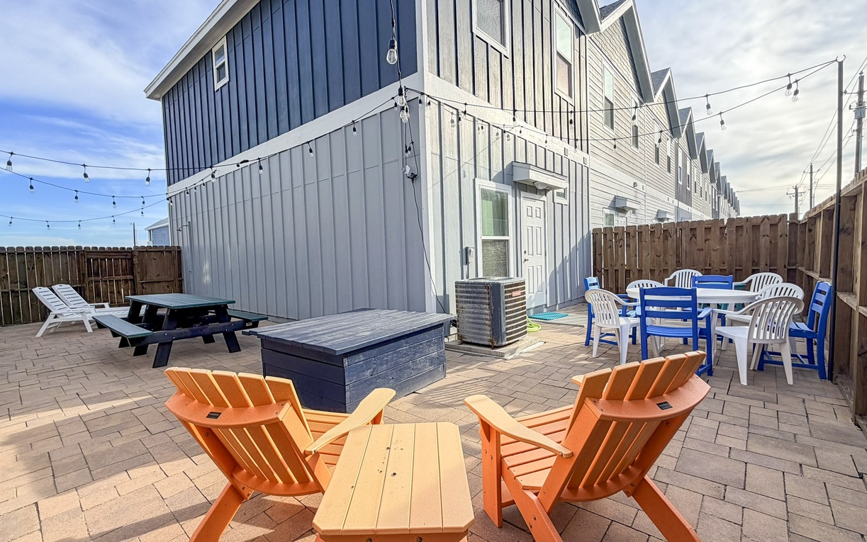 Spacious paver patio with colorful seating, picnic table, and string lights creates the perfect outdoor entertaining space for your group.
