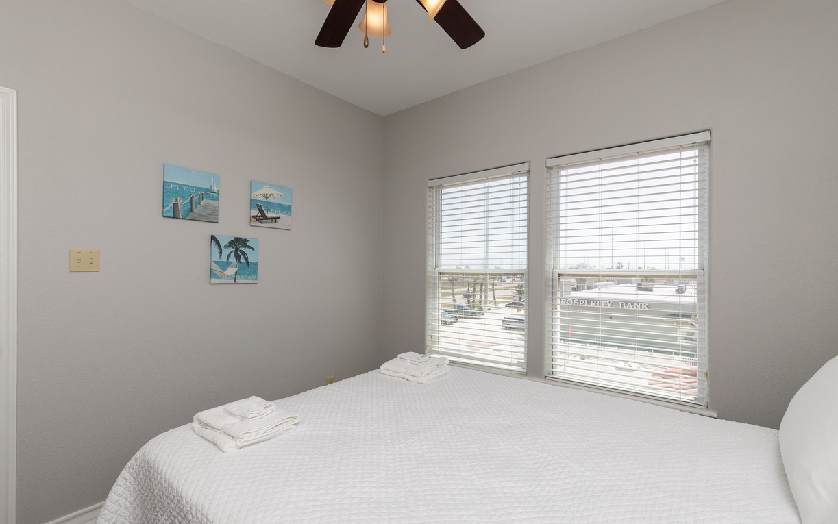 Wake up refreshed in your serene bedroom with city views and coastal artwork creating a peaceful retreat.