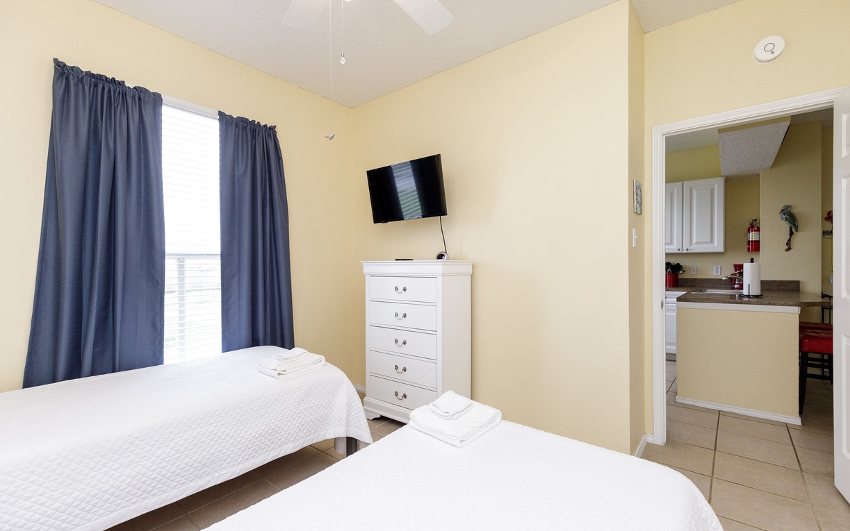 Relax in your bright twin bedroom with crisp linens, entertainment, and convenient kitchen access for effortless vacation stays.