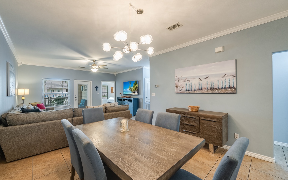 Gather around your elegant dining table where coastal art meets modern comfort in this open-concept living space.