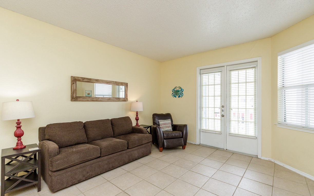 Settle into your spacious living room with comfortable seating and natural light streaming through French doors to your private balcony.