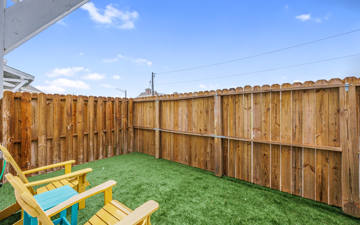 Step into your private backyard oasis with fresh artificial turf and cheerful yellow chairs where you can unwind under sunny skies.