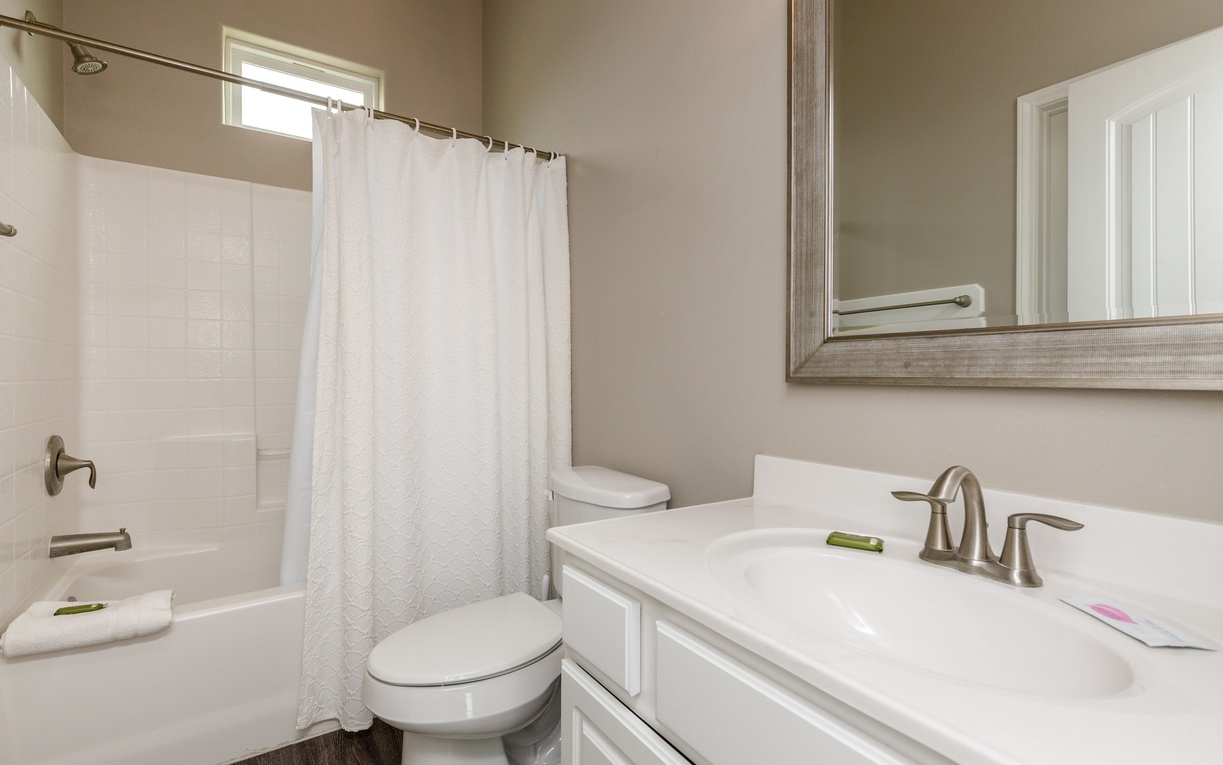 Step into your pristine bathroom with fresh towels, bright shower-tub combo, and elegant vanity—your perfect retreat after exploring.