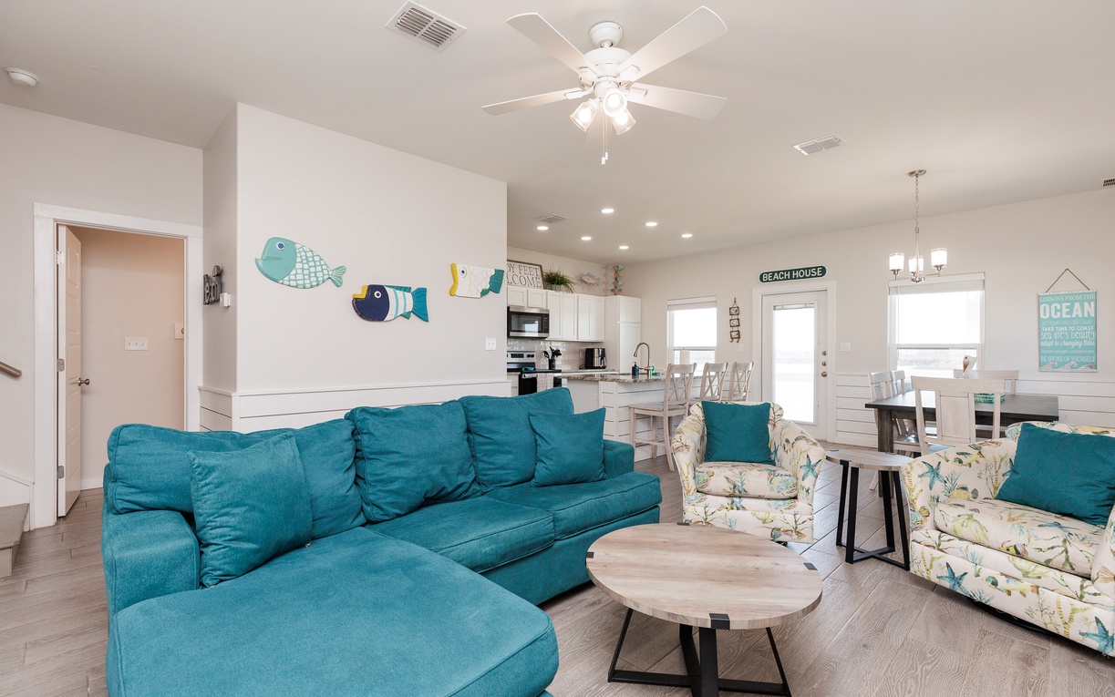 Relax in your bright, coastal-inspired living space featuring a plush turquoise sectional and cheerful beach decor that instantly makes you feel at home.