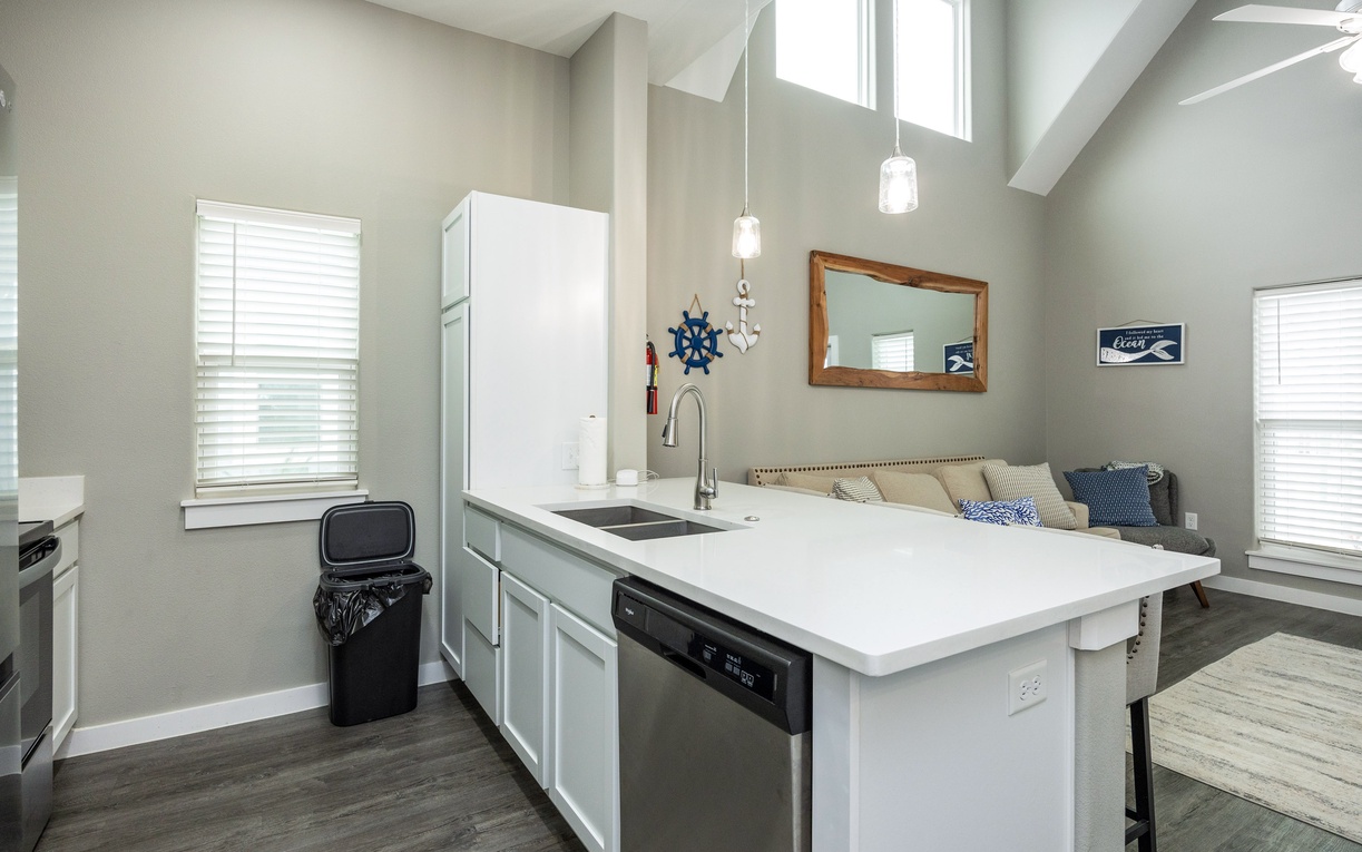 Your bright kitchen features white counters, modern appliances, and pendant lighting, with a cozy living area steps away for easy entertaining.