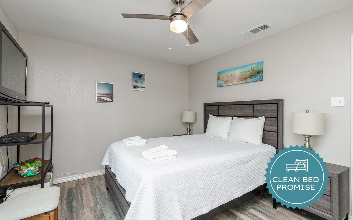 Rest easy in your stylish bedroom with crisp linens, tropical artwork, and a gentle ceiling fan for perfect comfort.