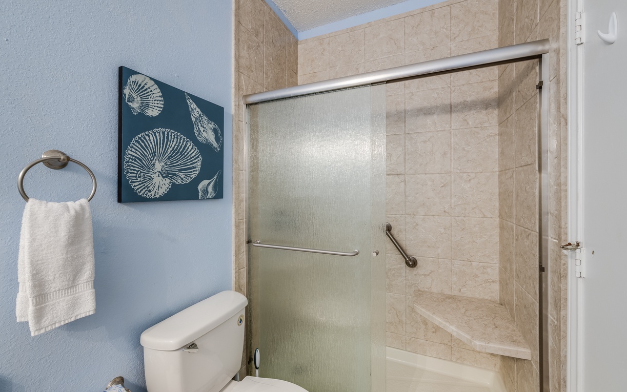 En-suite bathroom featuring a spacious walk-in shower with grab bars and a built-in bench for added comfort and convenience.