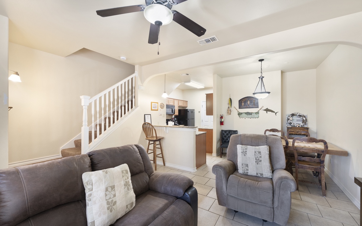 Settle into your open-concept living area with plush seating, ceiling fan, and tile flooring. The kitchen and dining space flow seamlessly, making your stay feel like home.