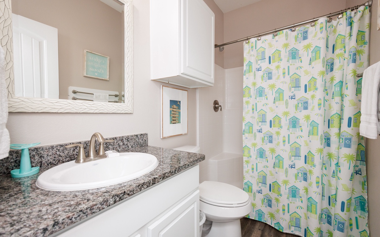 Refresh in your bright, coastal-themed bathroom with granite counters and cheerful beach hut shower curtain that brings seaside charm to your morning routine.