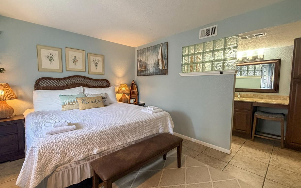 Sink into your coastal retreat's plush king bedding and wake refreshed in this serene bedroom featuring warm wicker accents and tropical charm.
