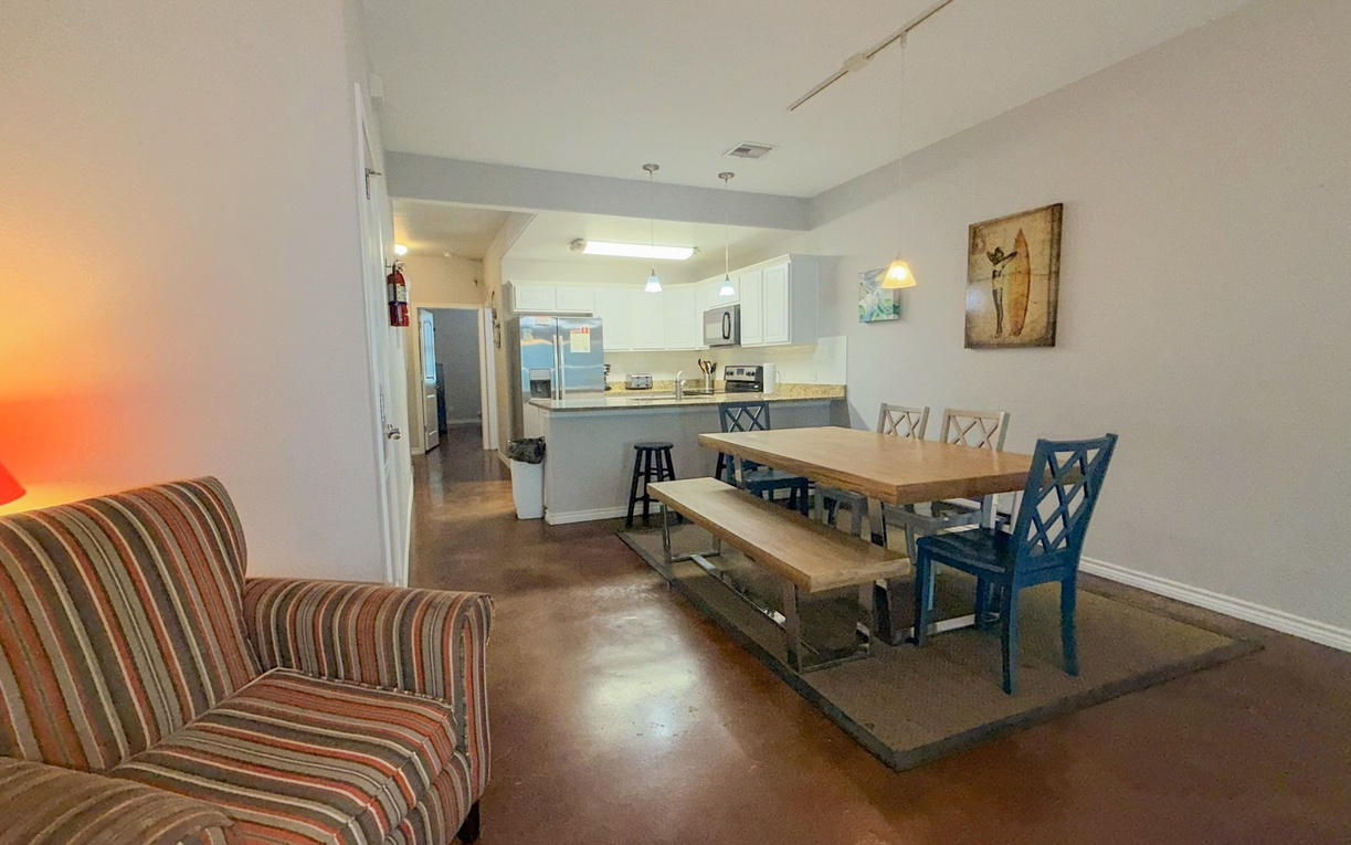 Relax in your open-concept living space where cozy striped seating flows seamlessly into a modern dining area and fully-equipped kitchen.