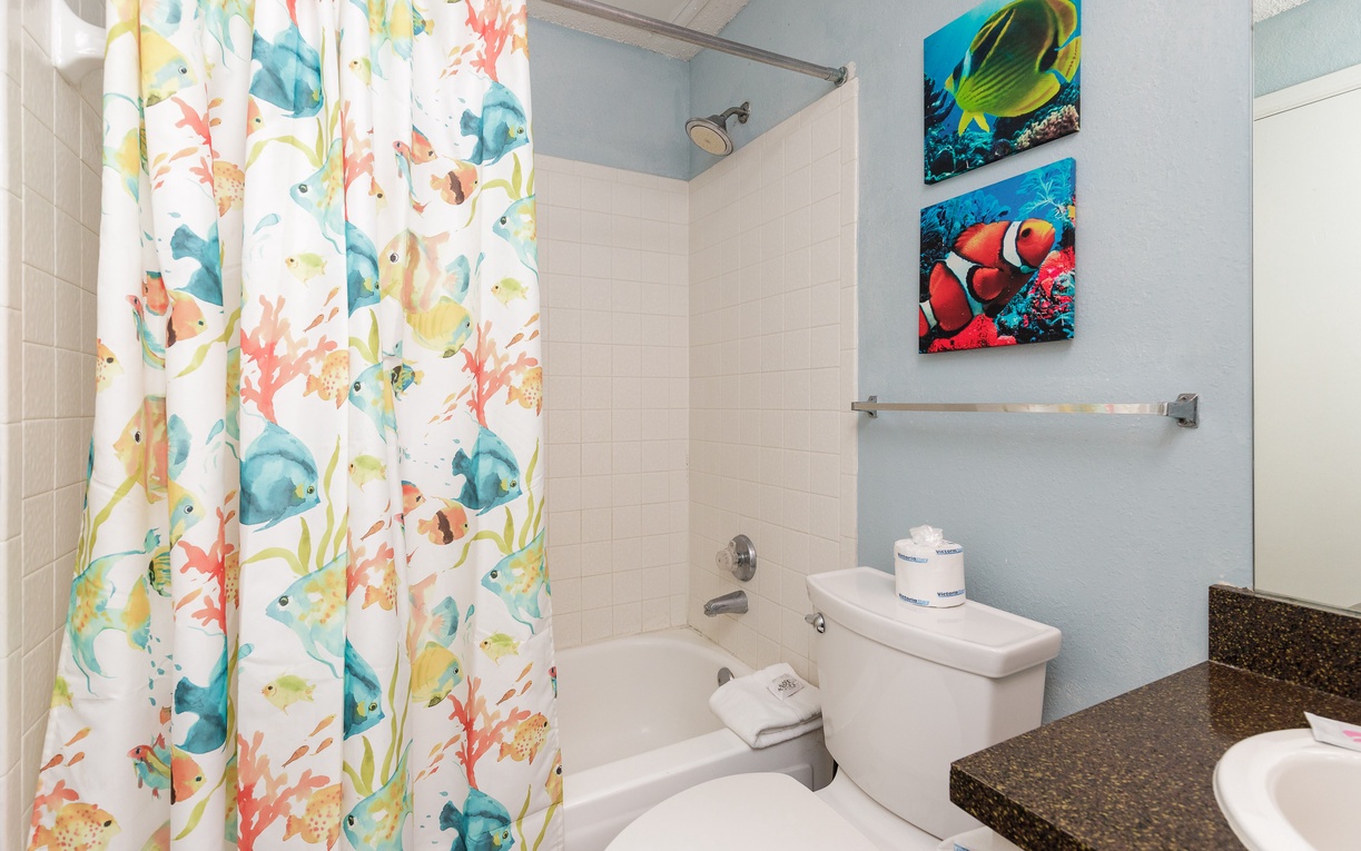 Step into your vibrant bathroom featuring a whimsical tropical fish shower curtain and colorful underwater artwork that transforms your daily routine into an ocean adventure.