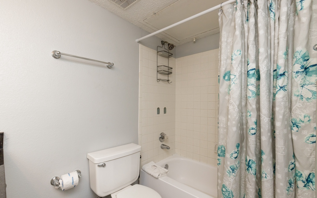 Your private bathroom features a relaxing tub-shower combo with convenient storage and coastal-inspired decor.