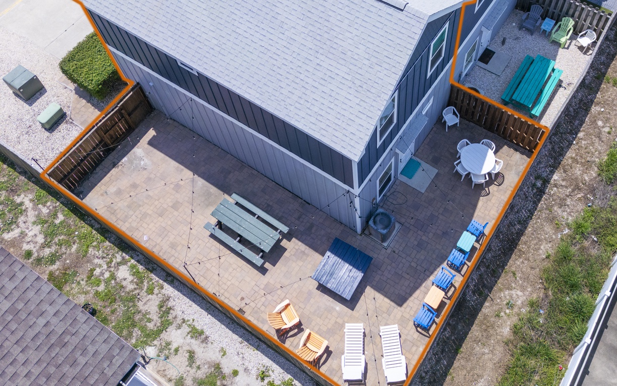 Aerial view showcasing the vacation rental property with its spacious patio featuring outdoor furniture, lounge chairs, and entertainment areas.