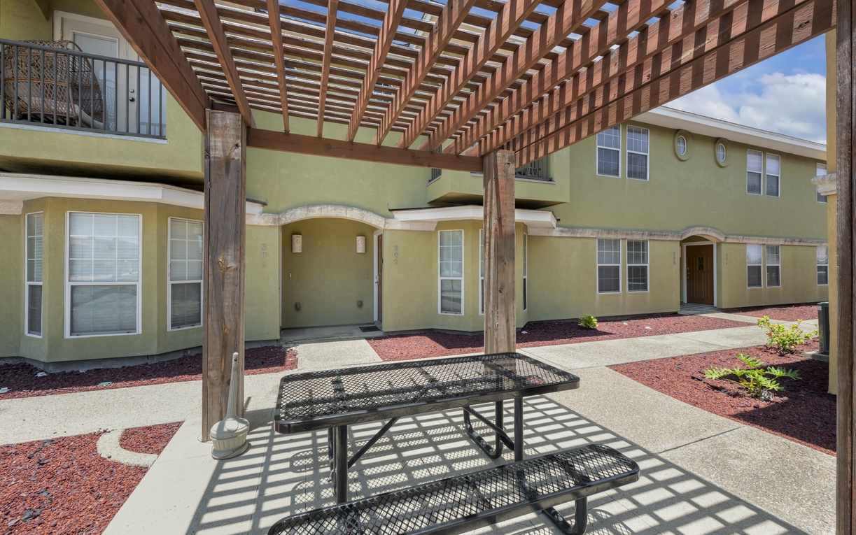 This inviting shared courtyard offers shade and a peaceful spot to relax between your units. Natural wood pergola and mulched landscaping create a clean, quiet retreat.