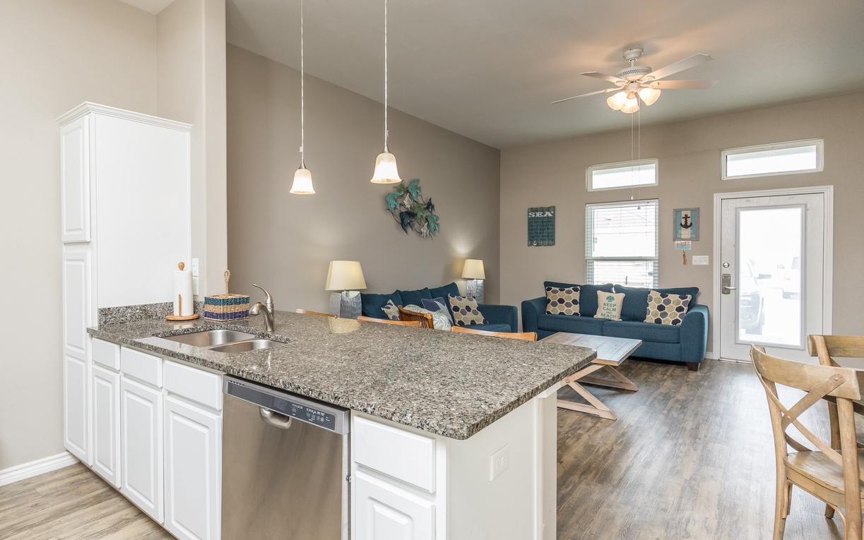 Step into your open-concept haven where granite counters and coastal blues create the perfect backdrop for your beach getaway memories.