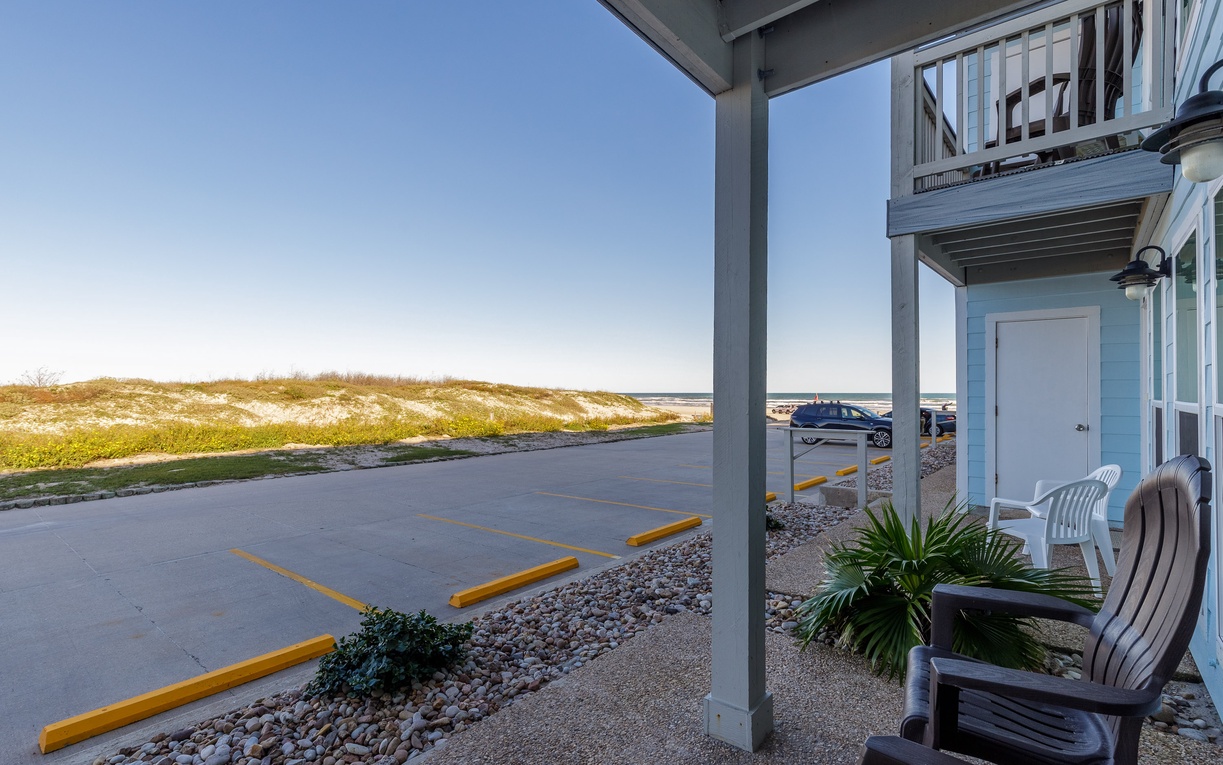Your ground-floor patio offers white plastic chairs perfect for enjoying coastal breezes, with sand dunes and ocean views just steps away.