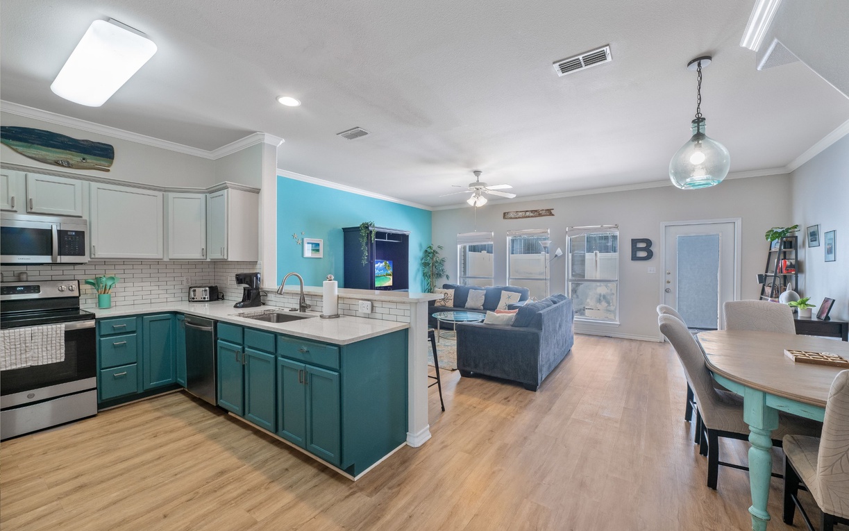 Your spacious open-concept retreat flows seamlessly from the stylish turquoise kitchen to comfortable living space, perfect for gathering and creating memories together.