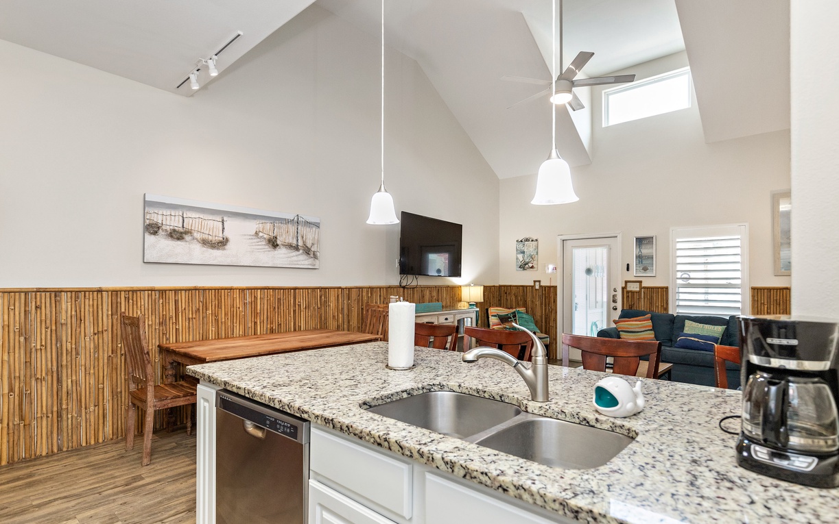 Your open-concept kitchen flows seamlessly into the living area, where soaring ceilings and coastal charm create the perfect vacation atmosphere.