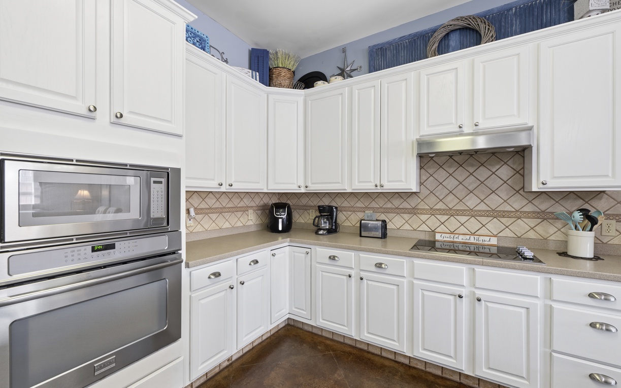 Your fully equipped kitchen features white cabinetry, stainless appliances, and a charming tile backsplash—perfect for preparing meals and gathering over morning coffee.