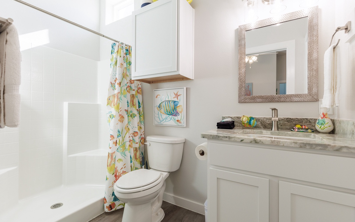 Your coastal-themed bathroom features a spacious walk-in shower, elegant granite vanity, and cheerful tropical fish decor to brighten your morning routine.