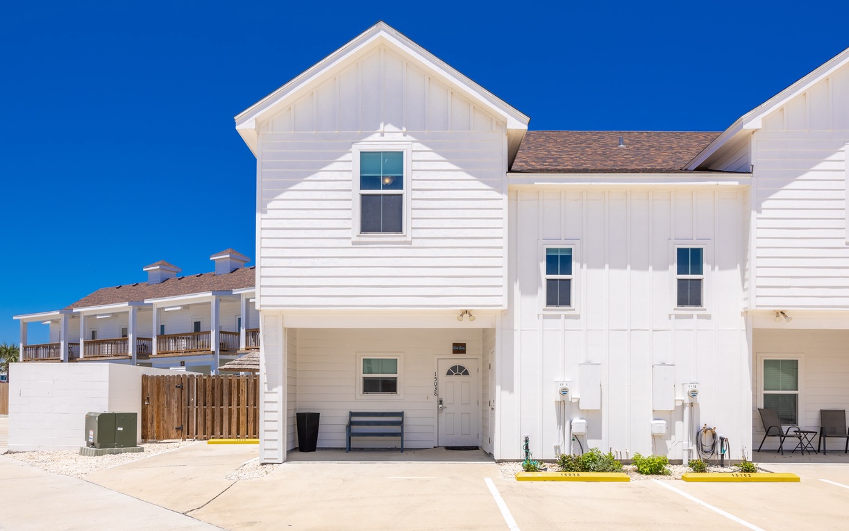 Modern townhouse-style vacation rental with clean white exterior and convenient parking in a peaceful residential setting.