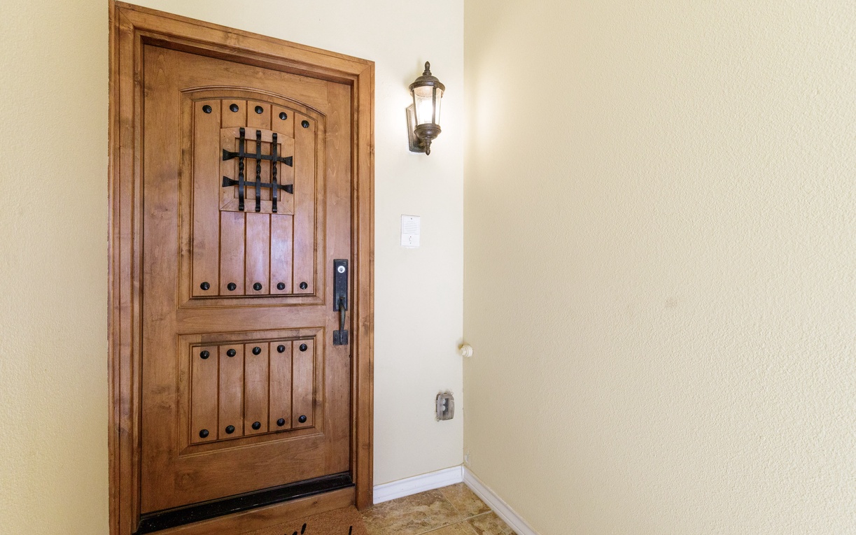 Impressive wooden entrance door with decorative iron details welcomes arrivals to this vacation rental property.