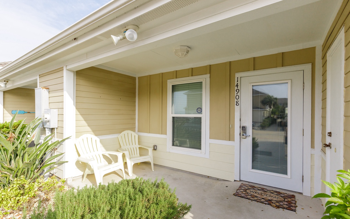 Step onto your private covered porch where comfortable seating awaits among lush greenery—the perfect spot to unwind with morning coffee.