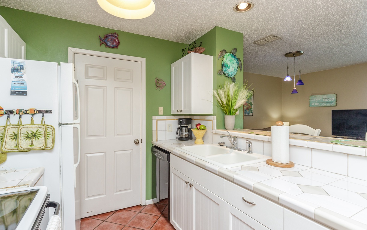 Your bright coastal kitchen awaits with tropical charm, white cabinets, and cheerful green accents perfect for preparing beachside meals.