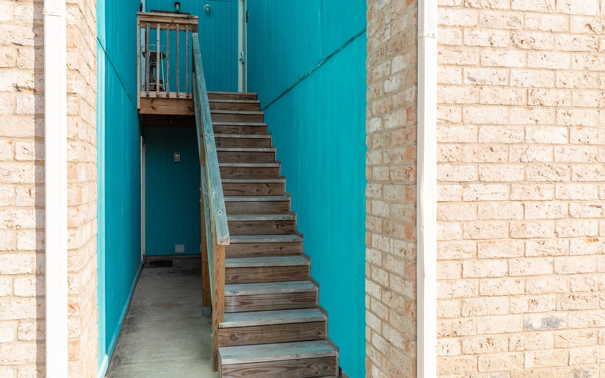 Charming wooden staircase with vibrant turquoise walls creates a welcoming pathway to your upstairs retreat.