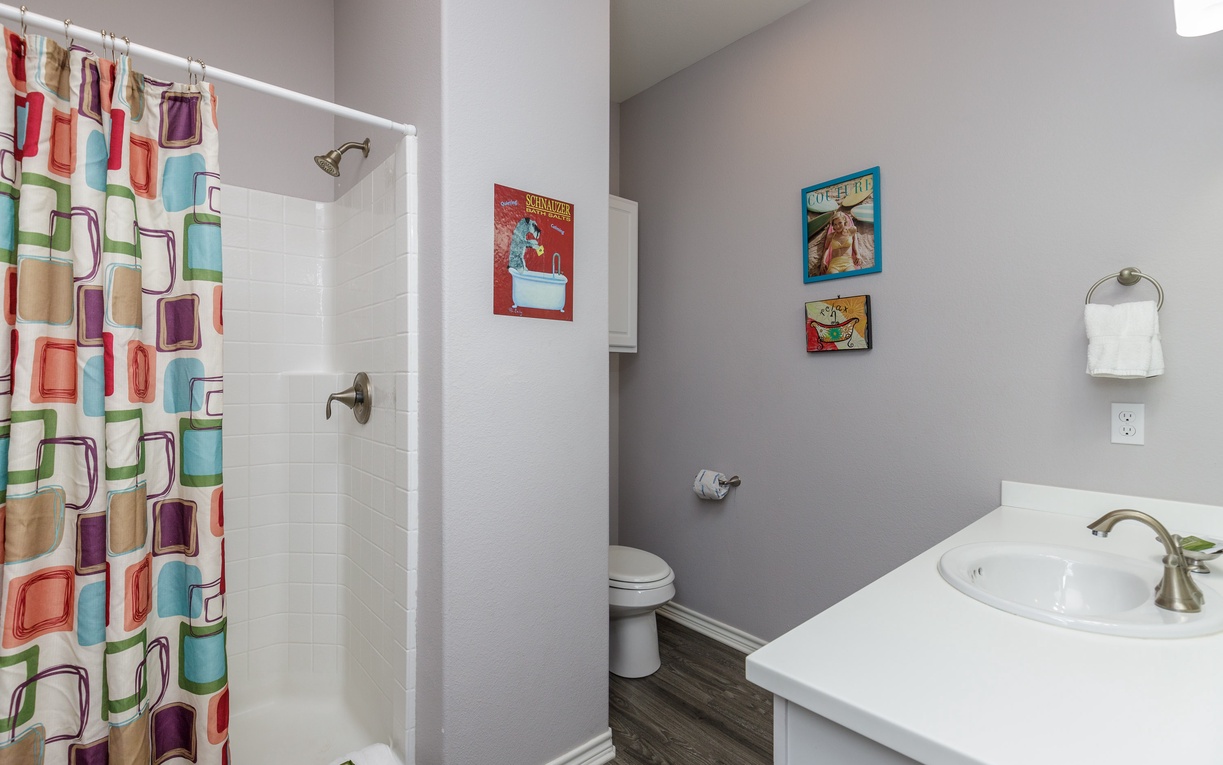 Fresh and modern bathroom with colorful shower curtain, clean fixtures, and charming vintage-style wall art to brighten your morning routine.