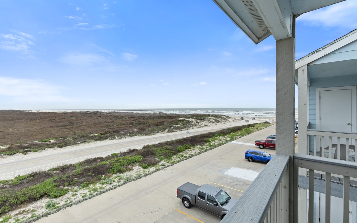 Ocean view from covered balcony with beach access and parking below.