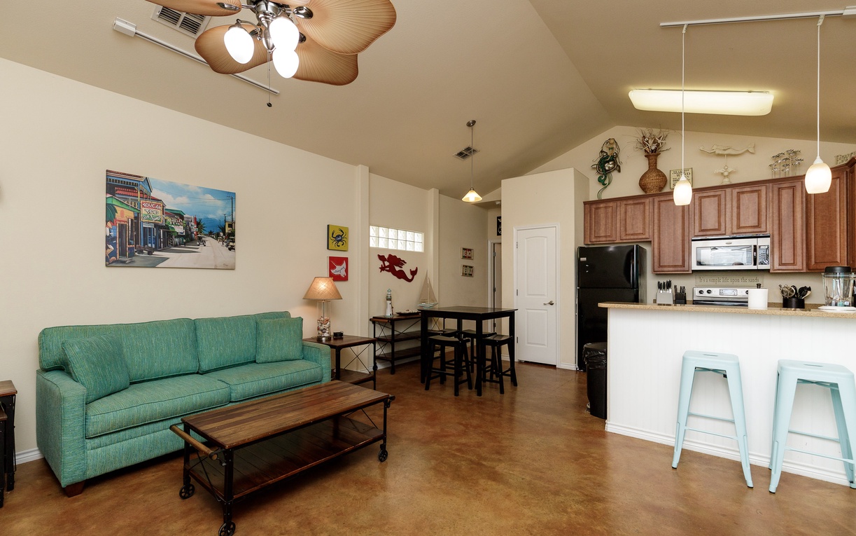 Relax in your open-concept living space where coastal-inspired decor meets modern comfort, complete with a fully equipped kitchen and cozy seating area.