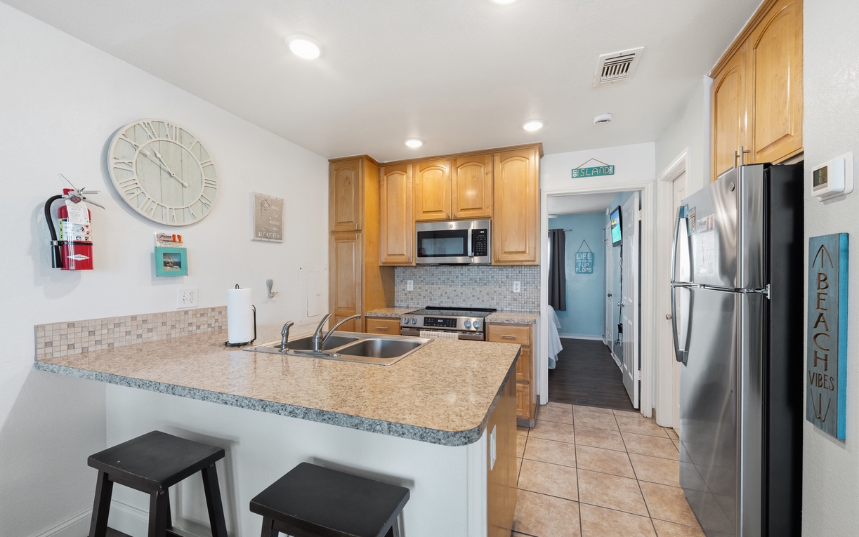 Your beach-inspired kitchen awaits with granite countertops, stainless appliances, and a breakfast bar for morning coffee—charming seaside touches make it feel like home from the moment you arrive.