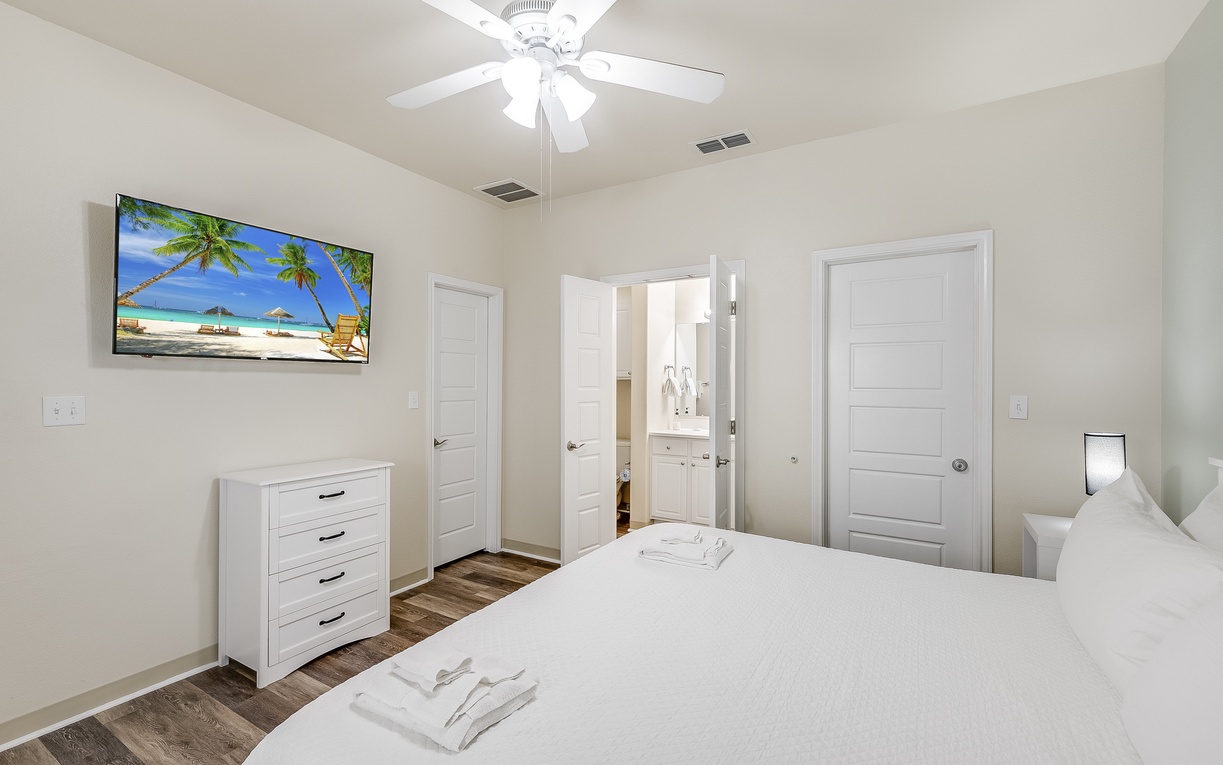 Unwind in your serene bedroom with tropical vibes on the wall-mounted TV, soft towels waiting, and an en-suite bathroom just steps away.