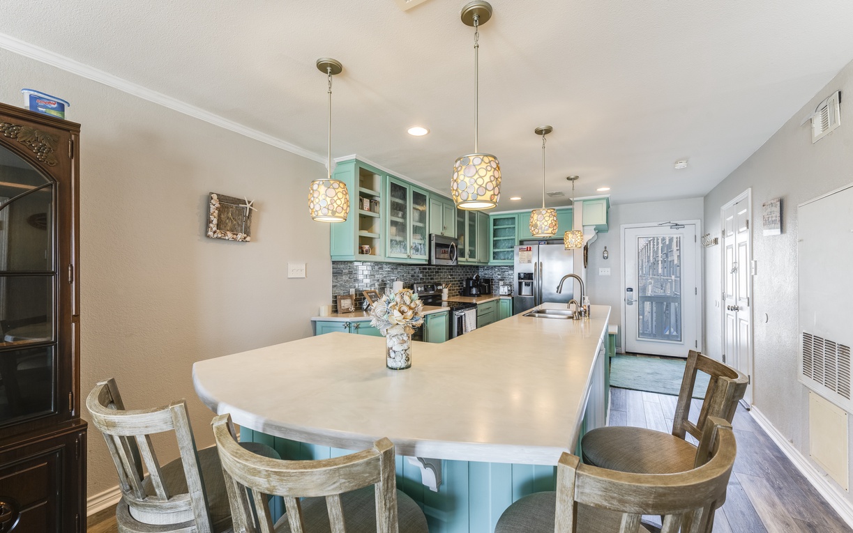 Your spacious kitchen awaits with charming turquoise cabinets, pendant lighting, and a large island perfect for cooking together.