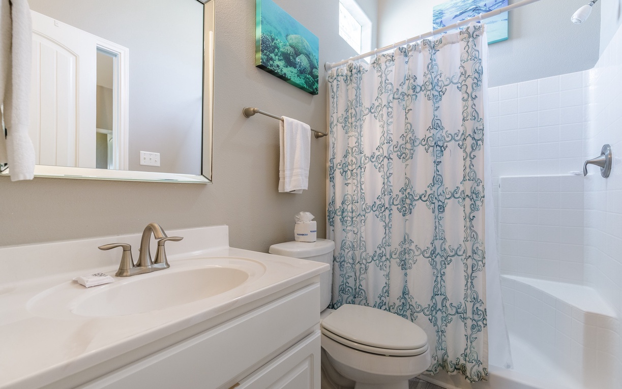 Refresh in your private bathroom featuring a pristine tub-shower combo and charming coastal artwork that sets a serene mood.