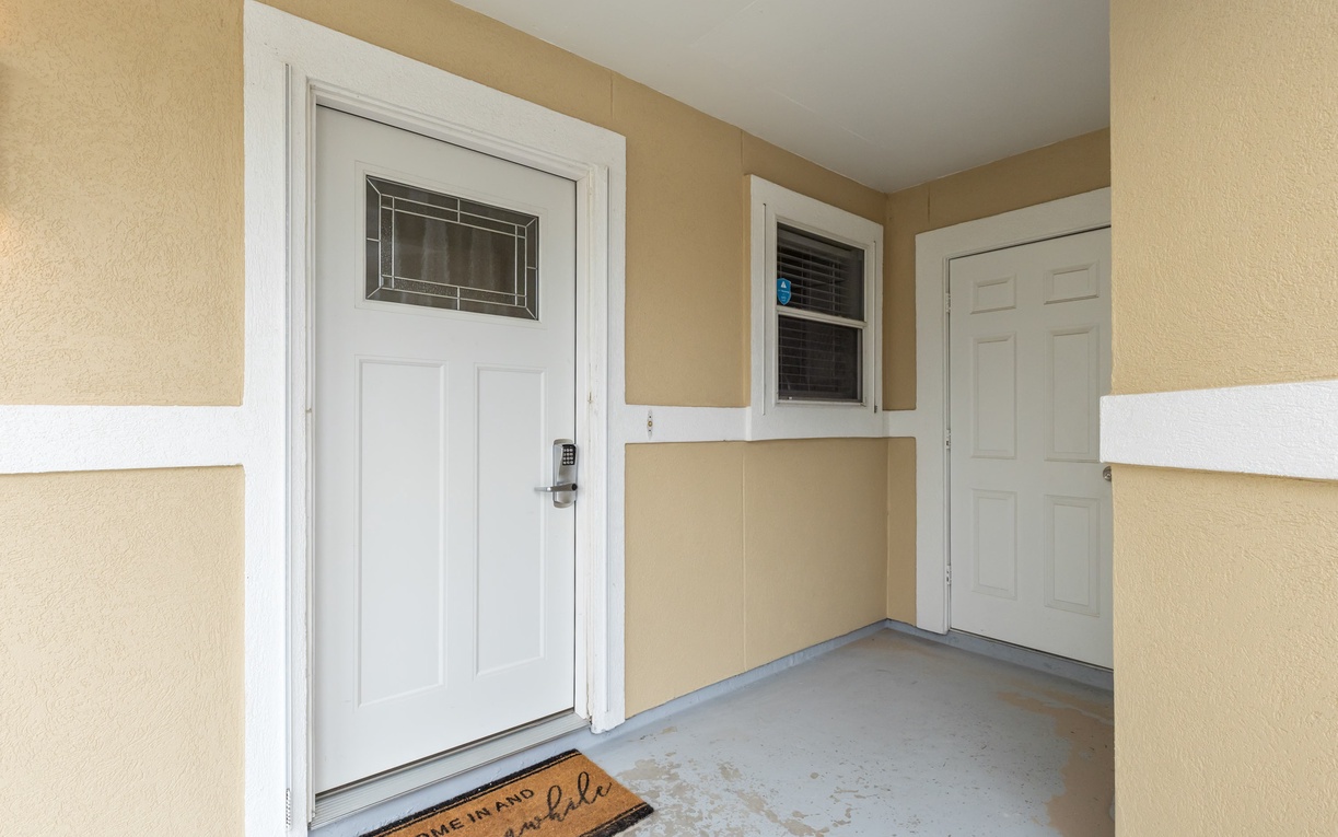 A welcoming entrance with warm beige and white exterior walls creates a charming arrival experience for your stay.