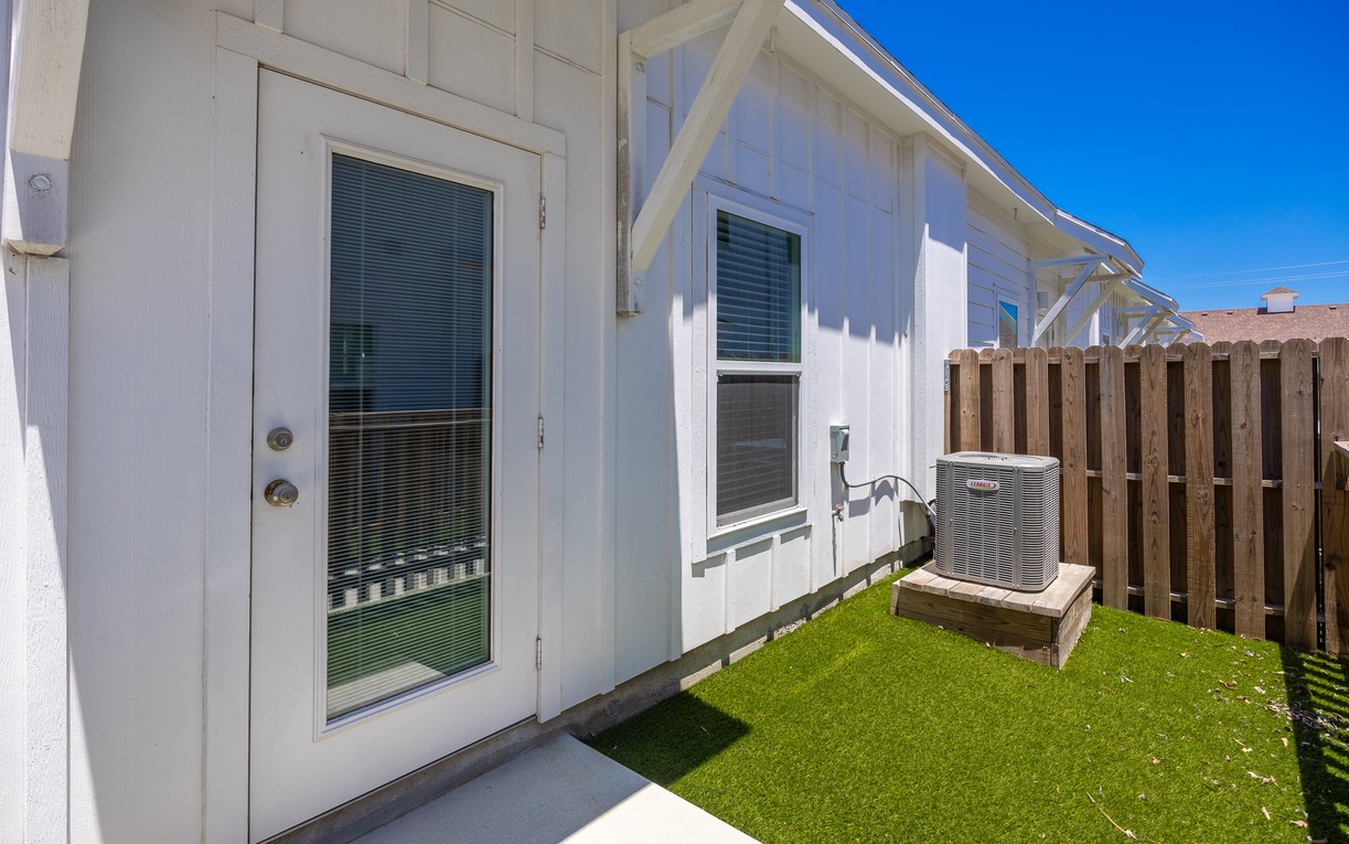 Clean white exterior with private outdoor space featuring artificial grass and wooden fence privacy.