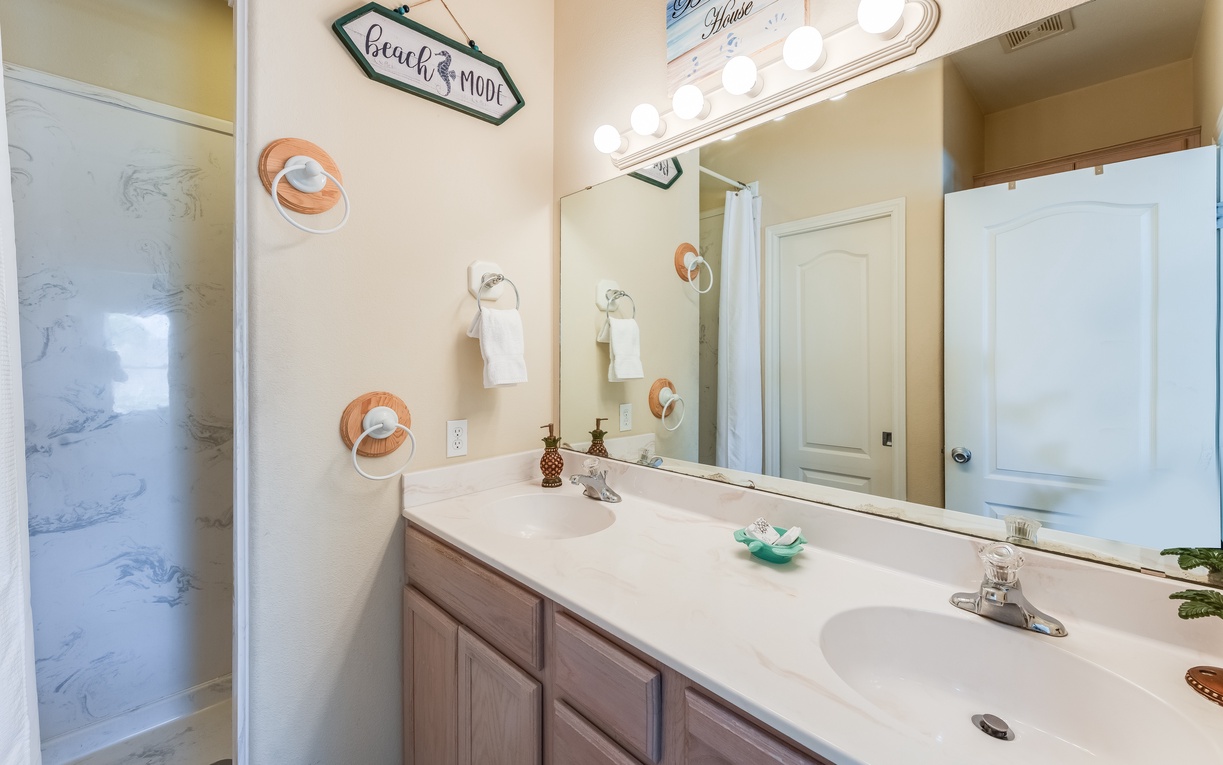 Your spacious bathroom features dual sinks and beach-themed touches that create a relaxing coastal retreat atmosphere.