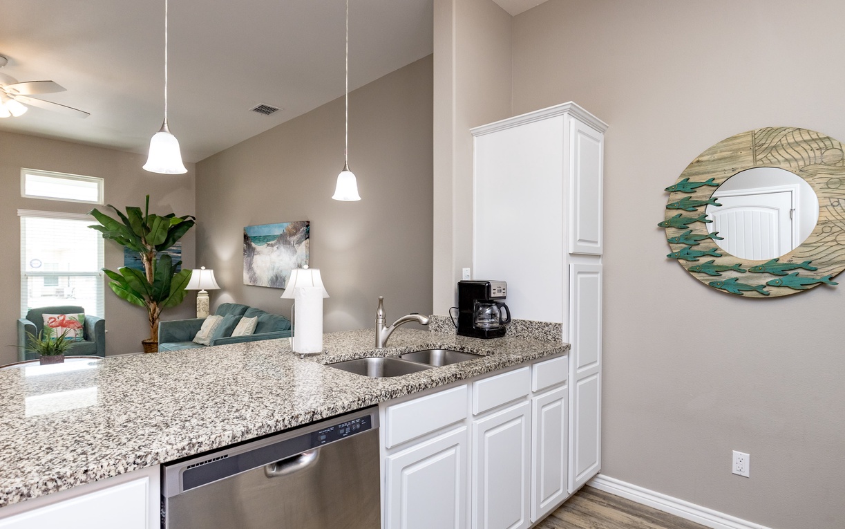 Your open-concept kitchen flows seamlessly into the living space, featuring granite countertops, white cabinetry, and modern appliances for effortless meal prep.