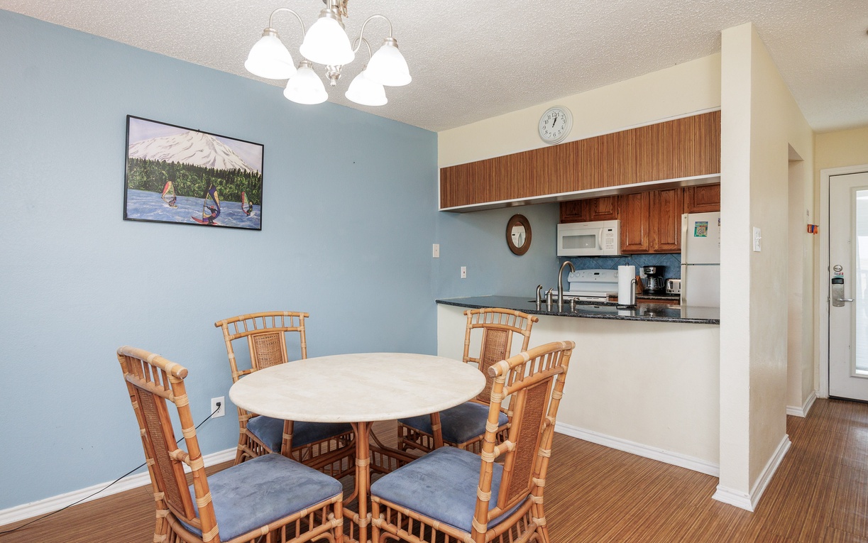 Your open dining area flows seamlessly into the fully equipped kitchen, perfect for preparing meals and gathering around the charming round table.