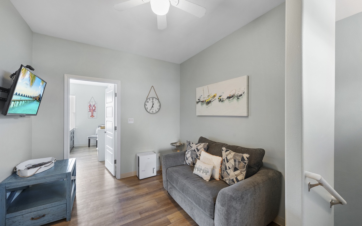 Unwind in your cozy living space with comfortable seating, wall-mounted TV, and charming coastal decor that sets the perfect vacation mood.